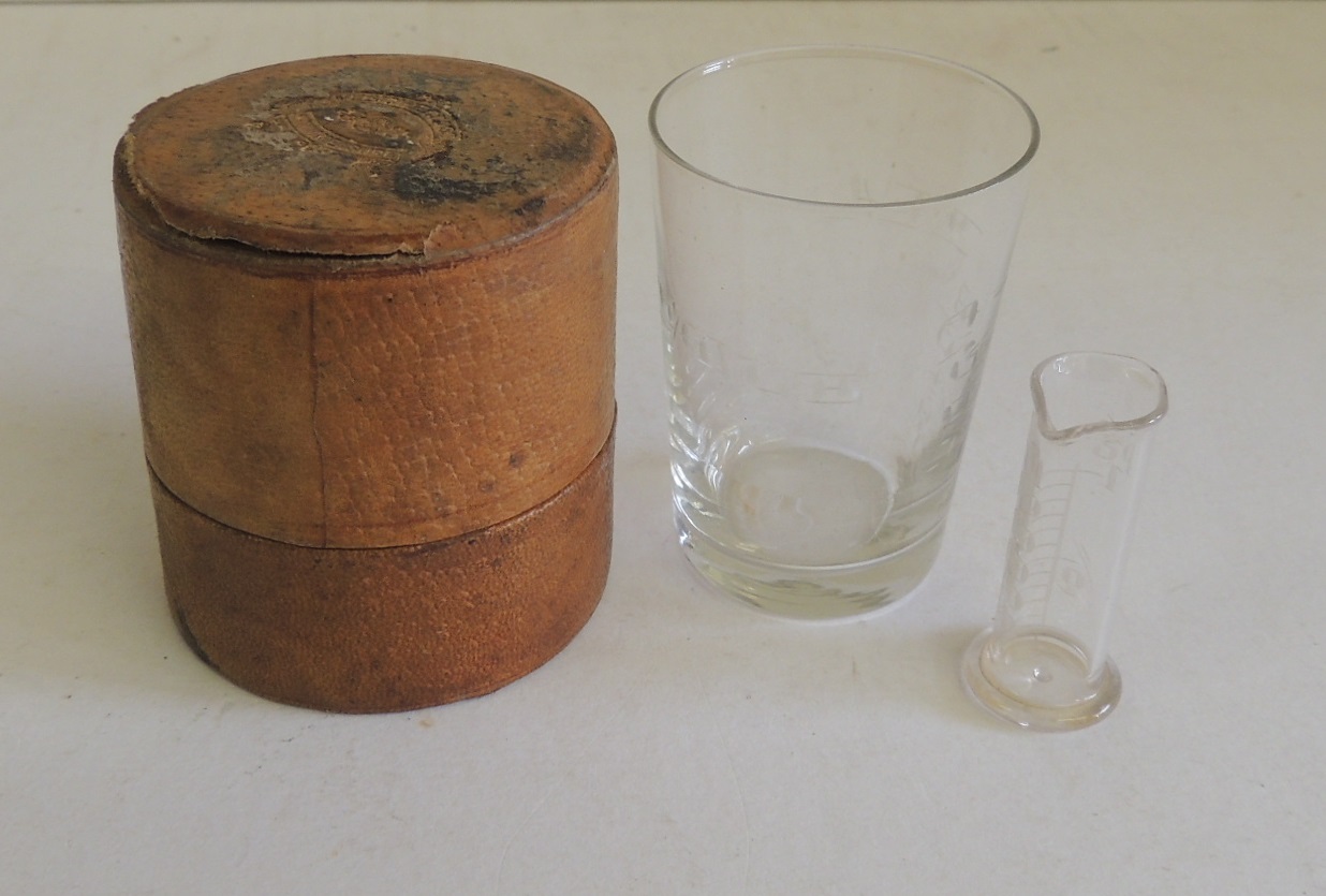 A medicine glass and minim measure in original pigskin covered case