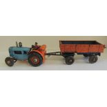A West German made battery operated tinplate tractor and side tipping trailer, with driver, 44cms