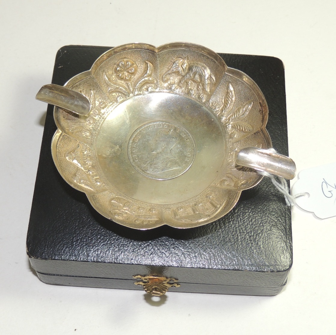 A cased, Indian white metal ashtray the centre set with a "one rupee" coin 1916, the sides