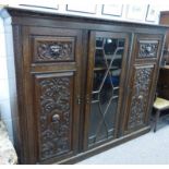 20TH CENTURY CARVED OAK BOOKCASE OF CENTRALLY SET ASTRAGAL GLASS PANEL DOOR, FLANKED BY 2 CARVED