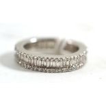 A diamond eternity ring, the band inset with baguette cut diamonds to the centre and a row of