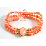 Coral bracelet, three rows of round beads with spacers at intervals, strung to an oval cabochon