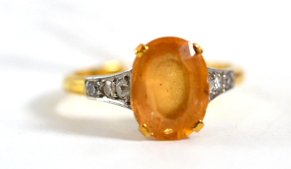 A topaz and diamond ring, the oval mixed cut topaz in a yellow four claw setting, with three eight-