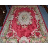 A Chinese carved rug, probably Peking, the crimson field of savonnerie design, centred by a