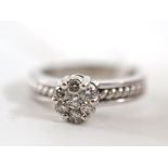 A diamond cluster ring, seven round brilliant cut diamonds in white claws on rope twist shoulders,