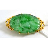 An 18ct gold jade brooch, carved with fruits and leaves, measures 3.9cm by 2.1cm