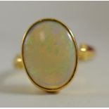 An opal ring, the oval cabochon opal in a yellow rubbed over mount, to shaped shoulders, on a
