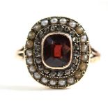 A garnet, diamond and seed pearl cluster ring, a cushion cut garnet  in a yellow rubbed over setting