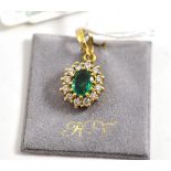An 18ct gold emerald and diamond pendant, the oval mixed cut emerald within a border of round