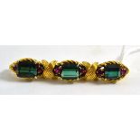 A tourmaline and ruby brooch, three step cut green tourmaline each within a pair of rubies, in