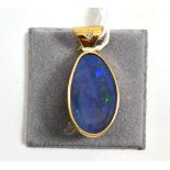 A 9ct gold opal doublet pendant, an asymmetric opal doublet in a yellow rubbed over setting, with