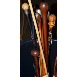 Bundle of walking sticks including ebonised examples and carved walking stick, the handle formed