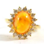 An 18ct gold fire opal and diamond cluster ring, a cabochon fire opal within a border of sixteen