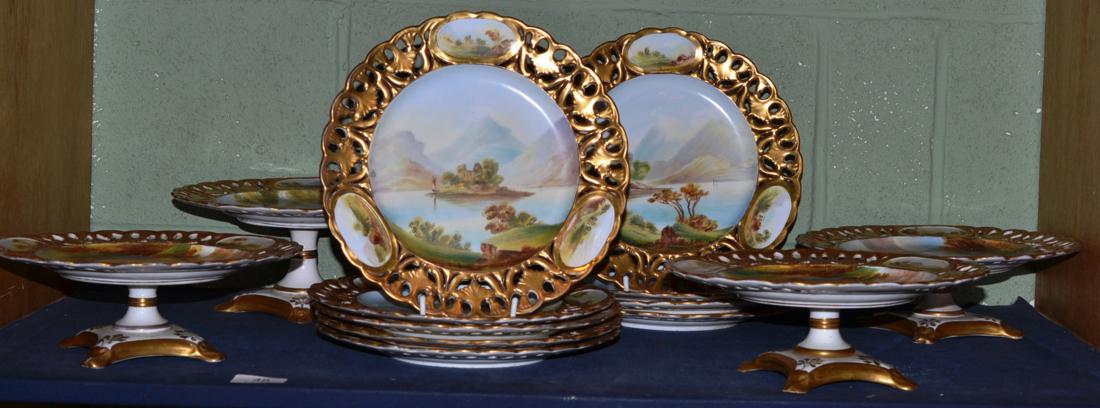 A Staffordshire porcelain dessert service, painted with landscapes within gilt pierced borders