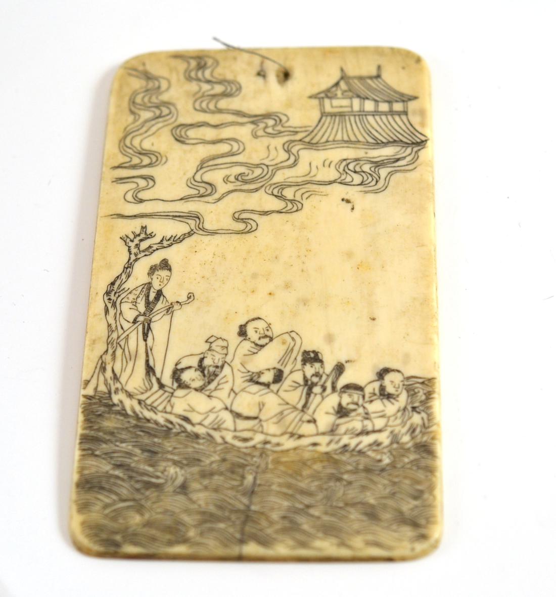 A Japanese carved ivory tablet, one side with figures on a boat, the other with Japanese characters,