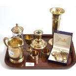 A silver mug, silver spill vase, silver loaded candlestick, napkin rings and silver spirit labels