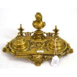 A cast and pierced brass inkstand, circa 1870, with a bust portrait flanked by two ink pots on a