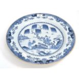 A Chinese porcelain charger, Quianlong, painted underglaze blue with figures in a fenced garden,