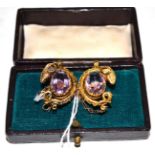 A Victorian amethyst brooch with ram's head motifs, two oval cut amethysts in yellow claw settings