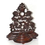 A large treen watch stand, highly decorated with leaves and fruit, stepped base with a single