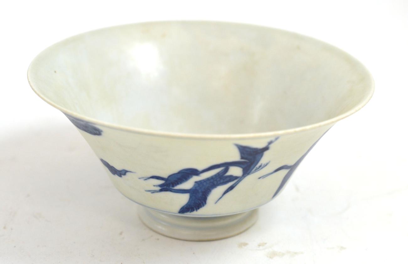 A Chinese porcelain bowl, decorated with four cranes flying amidst clouds and pine trees, bears