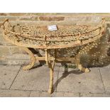 A Victorian cast iron demi-lune table, with wrythen gallery, strapwork top, leaf sheathed cabriole