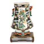 A Chinese famille vert/noir vase on wood stand