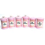 A Set of Six Pink Pottery Drug Jars, with shield shaped gilt labels, black lettering, four with