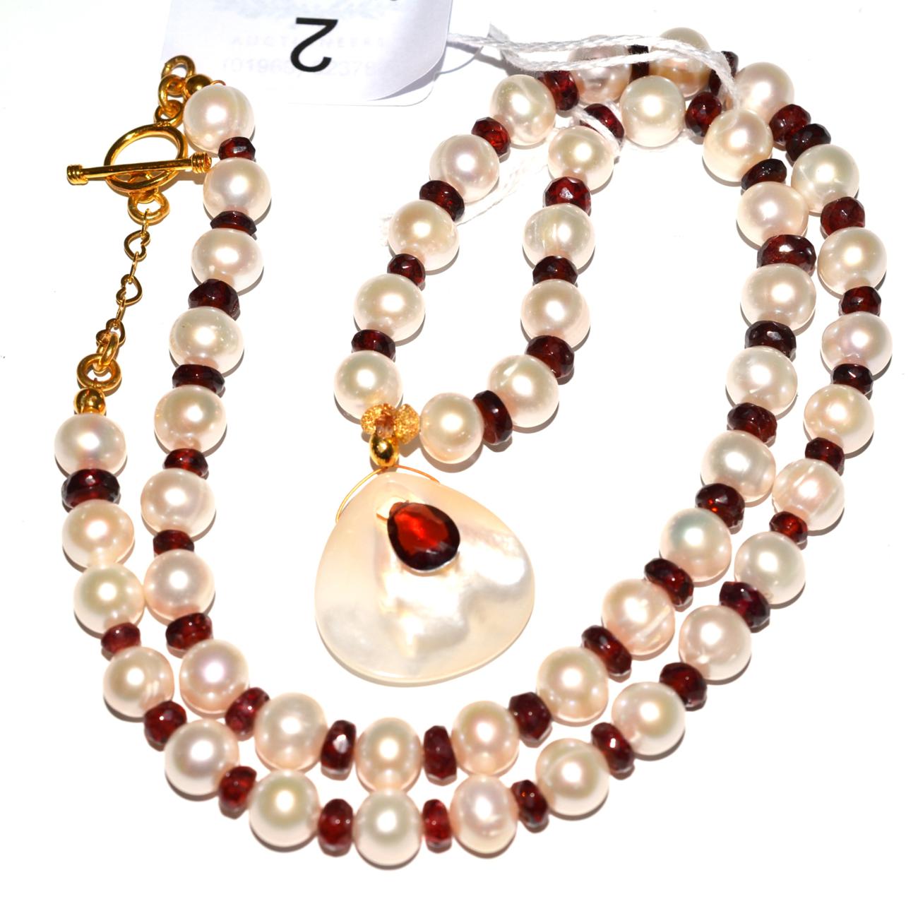 A garnet and cultured pearl necklace with pendant drop, the cultured pearls spaced with faceted