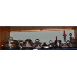 A shelf of assorted silver plate including entree dishes, toast rack, candlesticks, sauce boats,