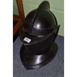 A copy of a medieval close helmet, in black painted steel, the two piece skull with raised comb,