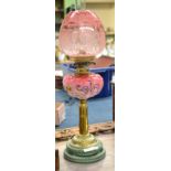 A Victorian brass oil lamp with pink reservoir and green ceramic base