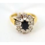 An 18ct gold sapphire and diamond cluster ring, an oval cut sapphire within a spaced border of