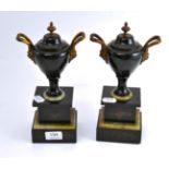 A pair of late 19th century twin handled urns on onyx and slate bases, 27cm high
