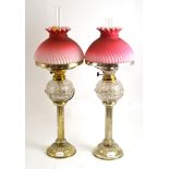 A pair of Hukin and Heath silver plated oil lamps with cut glass fonts and peach coloured satin