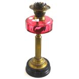 A Victorian oil lamp with a cranberry reservoir
