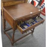 A 1920's oak two drawer table containing mainly silver-plated flatware and silver teaspoons