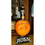 Painted shop display of a smiling, tongue-licking orange with eyes advertising Rossi, the French