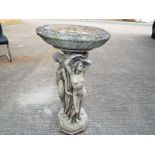 A stone bird bath with the base depictin