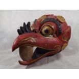 A carved wooden wall mask depicting the