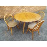 An Ercol oval drop-leaf dining table and four Ercol dining chairs