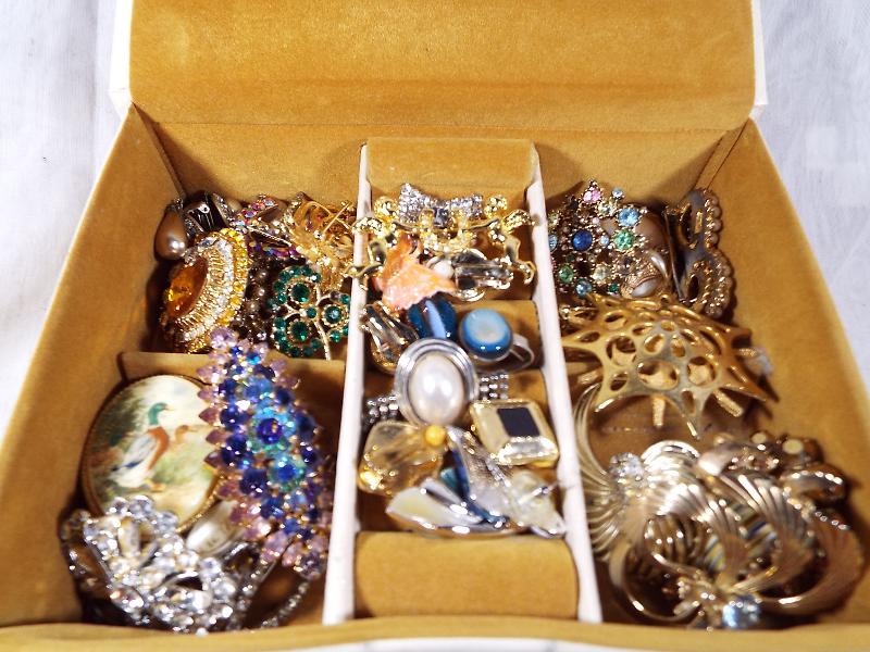 A jewellery box containing a quantity of good quality costume jewellery, predominantly brooches