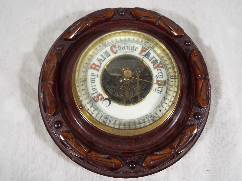 A wall mounted, oak cased, circular aneroid barometer