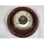 A wall mounted, oak cased, circular aneroid barometer