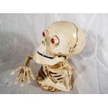 A cast iron novelty money bank in the form of a skull and partial skeleton