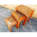 A nest of three glass topped tables, carved in an Oriental design