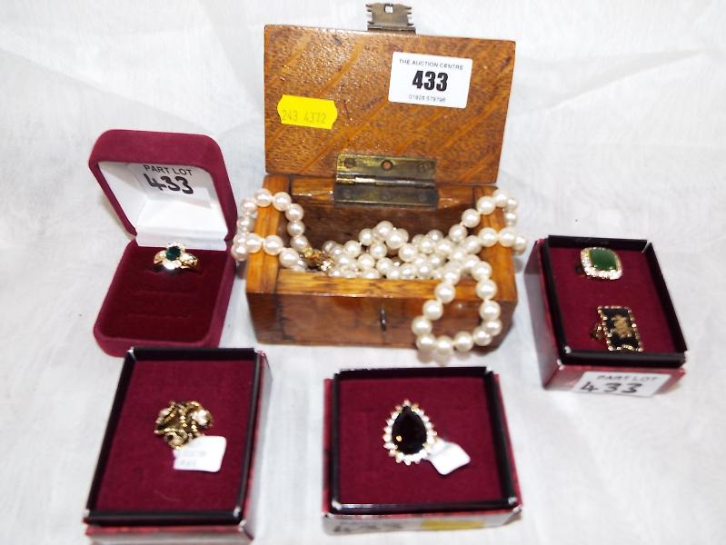 A miniature wooden chest containing two pearl necklaces and five yellow metal good quality rings