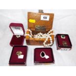 A miniature wooden chest containing two pearl necklaces and five yellow metal good quality rings