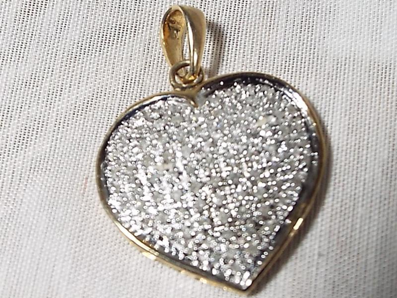 A lady's stone encrusted heart shaped pendant with gold mounts stamped 9k. with 1 k diamonds