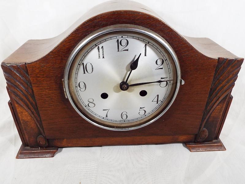An oak cased mantel clock with  silvered dial and chrome bezel, with key and pendulum Est £10 - £15